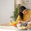 Indian mother and child enjoying a healthy meal together with fruits, vegetables, eggs, yogurt, oats and other nutritious foods on the dining table.