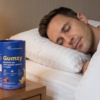 A man sleeping peacefully in bed next to a wooden nightstand holding a warm lamp and a blue bottle of Gumzy Melatonin and Ashwagandha sleep supplements.